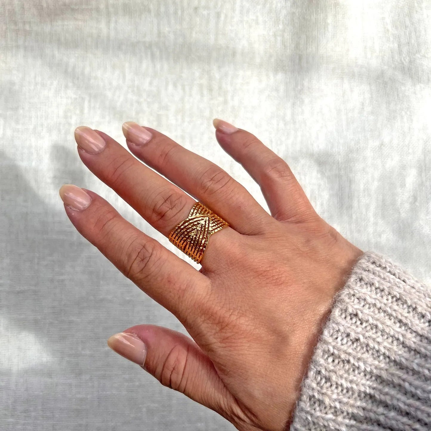 Bague Avenir ajustable, au design géométrique en acier inoxydable doré, portée au doigt.