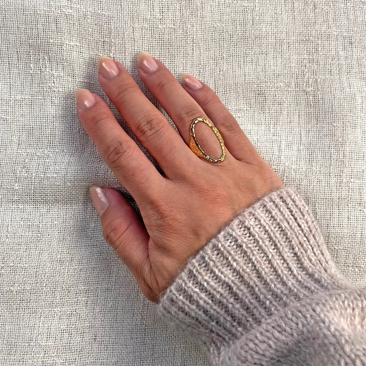 Bague Maintenant en acier inoxydable doré, forme ovale martelée, réglable, portée sur une main.
