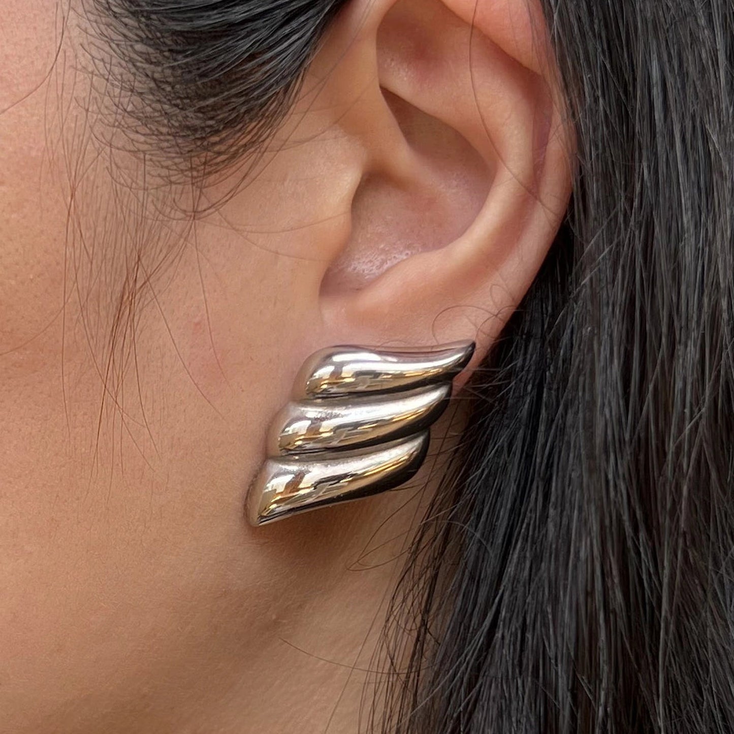 Boucles d'oreilles Elan doux argentées en acier inoxydable, délicatement portées à l'oreille.
