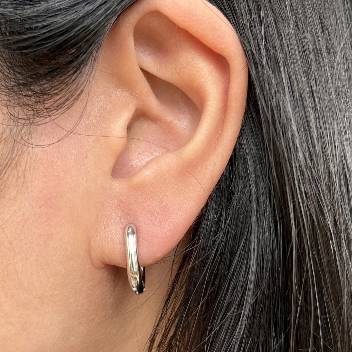 Boucles d'oreilles "J'existe" en acier argenté, au design modulable, portées à l'oreille.