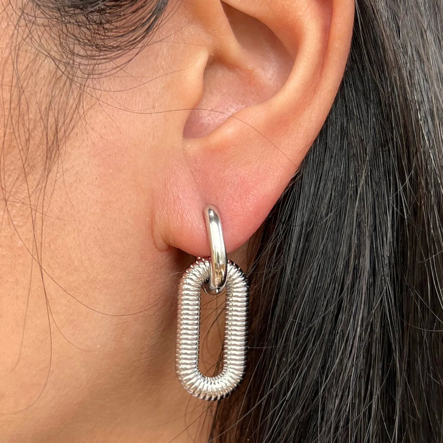 Boucles d'oreilles "J'existe" en acier inoxydable argenté, design modulable, portées à l'oreille.