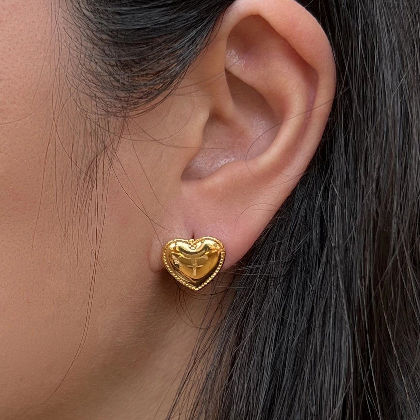 Boucles d'oreilles "L'intime" en forme de cœur doré à contour dentelé, en acier inoxydable, portées à l'oreille.