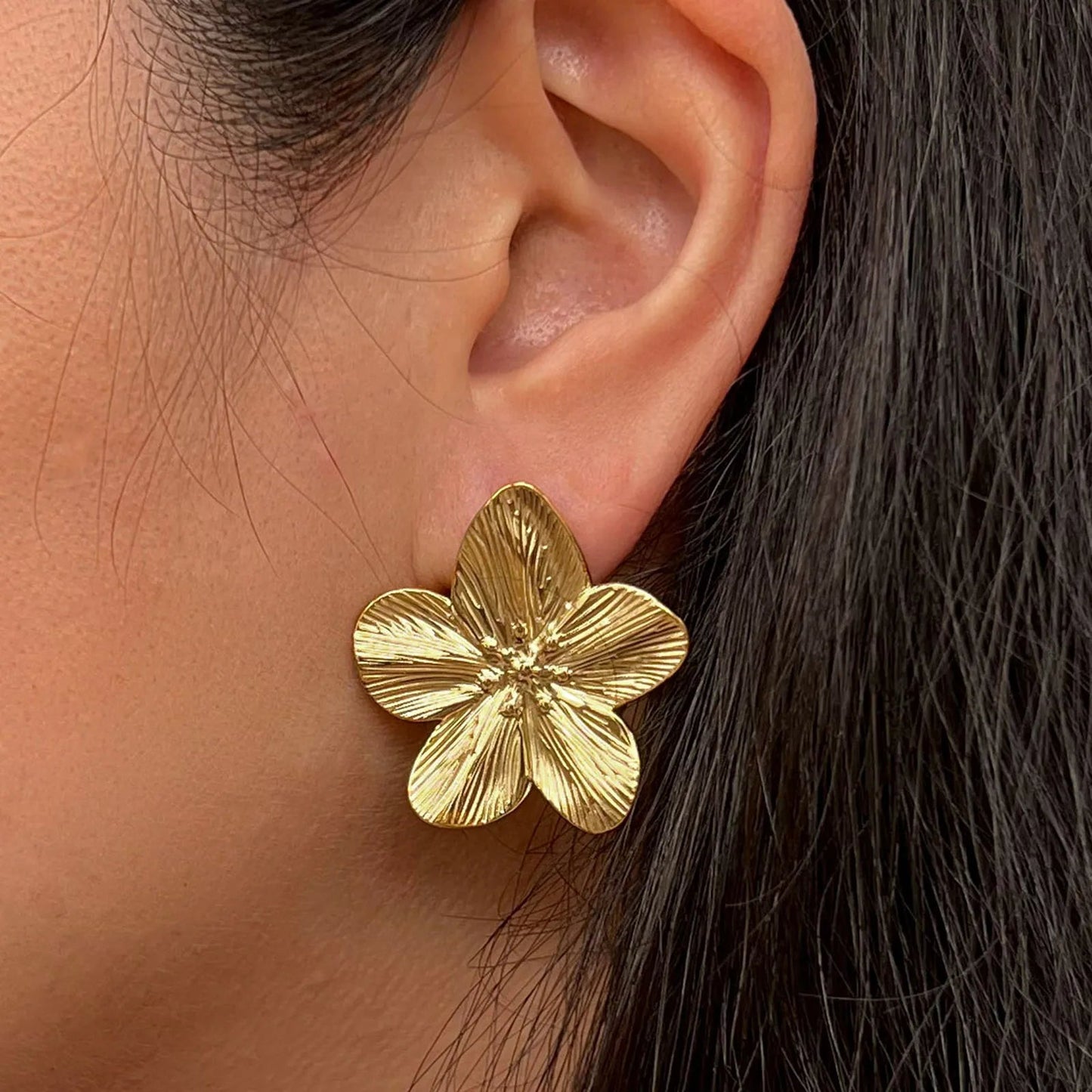Boucles d'oreilles Fleur de peau en acier inoxydable dorée, grand motif floral, porté.