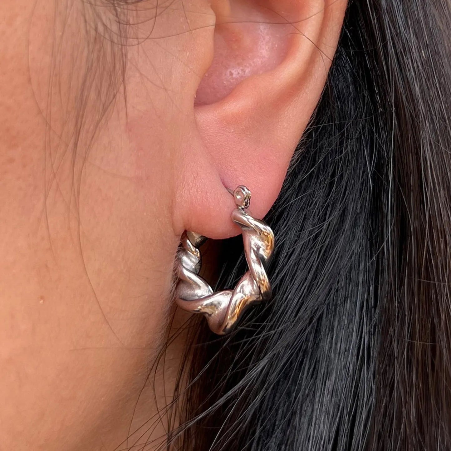 Boucles d’oreilles Elégante portées à l'oreille - créoles argentées ondulées en acier inoxydable.