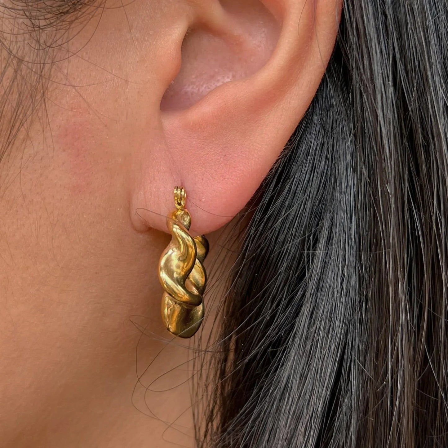 Boucles d’oreilles Elégante portées à l'oreille - créoles dorées ondulées en acier inoxydable.