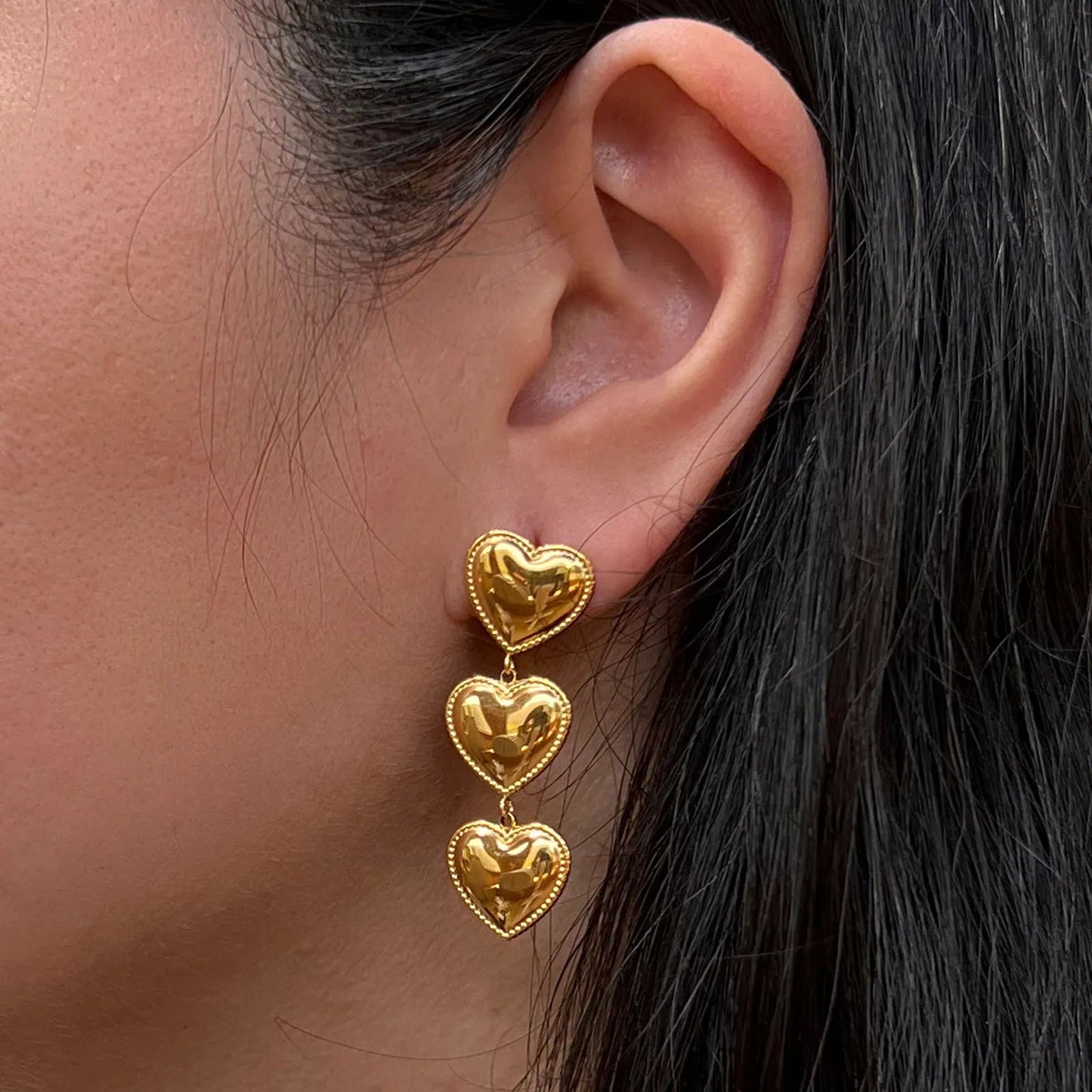 Boucles d'oreilles "Unique", en acier inoxydable doré, pendantes en coeurs, portées à l'oreille.