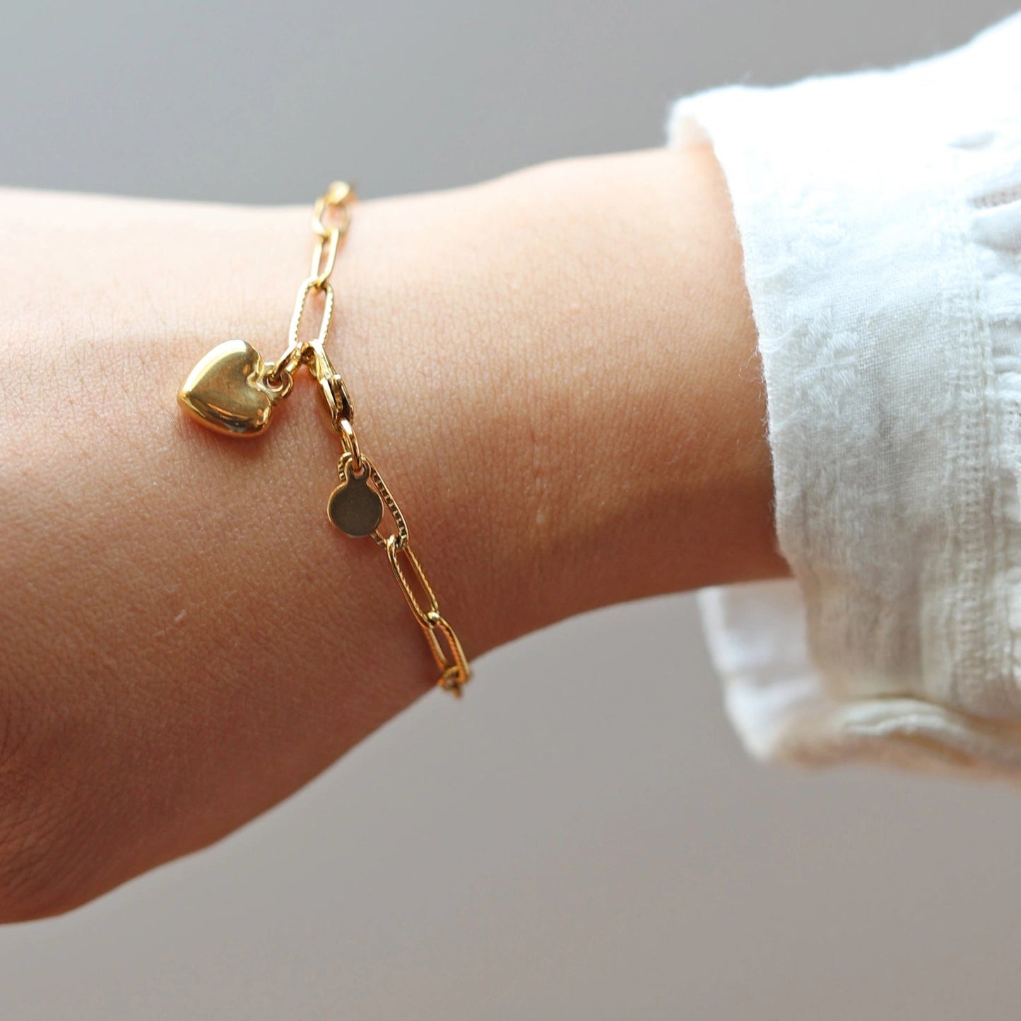 Bracelet Valeur acier inoxydable doré, avec breloque cœur personnalisable, porté au poignet.