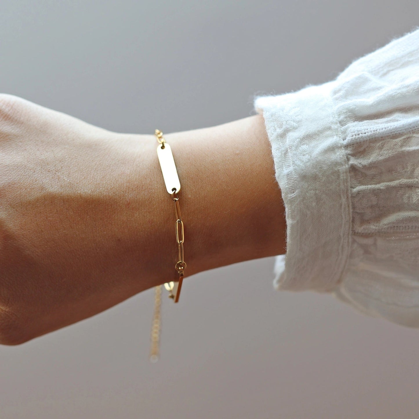 Bracelet "Expression" en acier inoxydable doré, orné de plaques personnalisables porté autour du poignet.