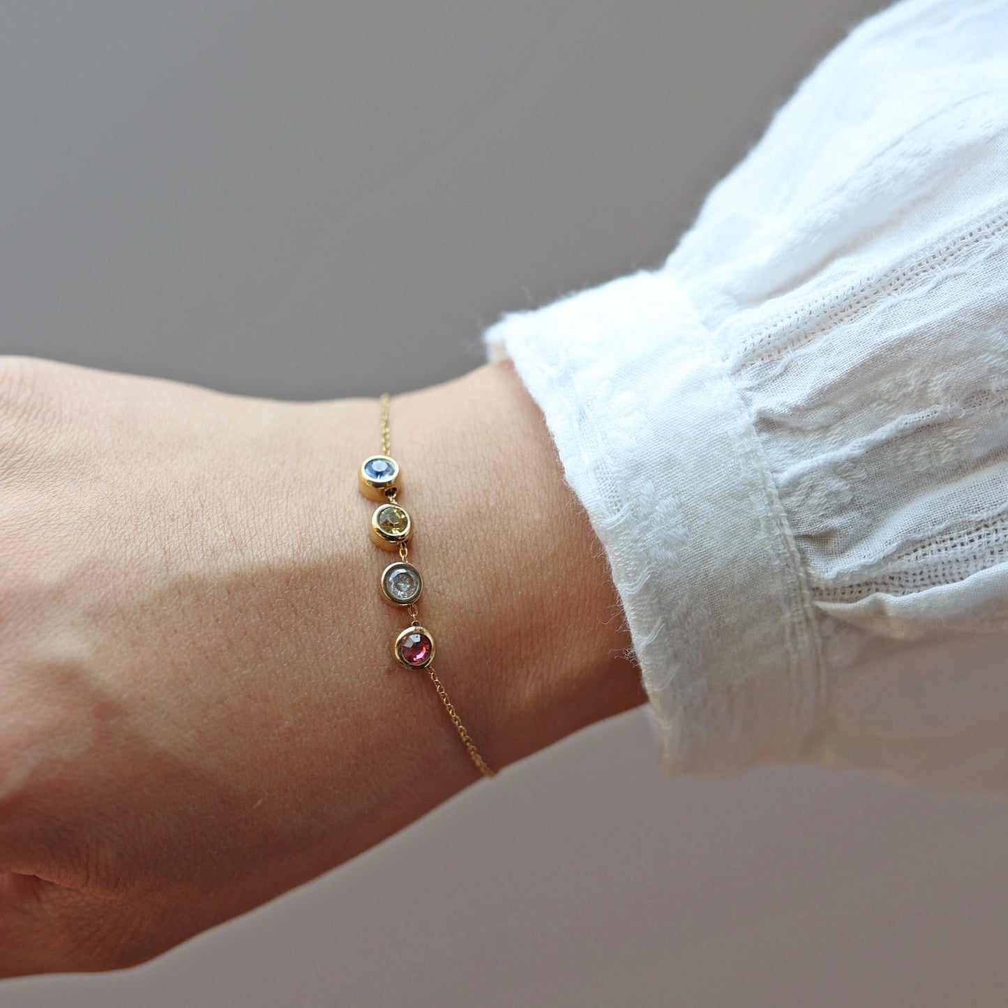 Bracelet "Mon intérieur" en acier doré, orné de pierres de couleurs coulissantes personnalisables, porté autour du poignet.