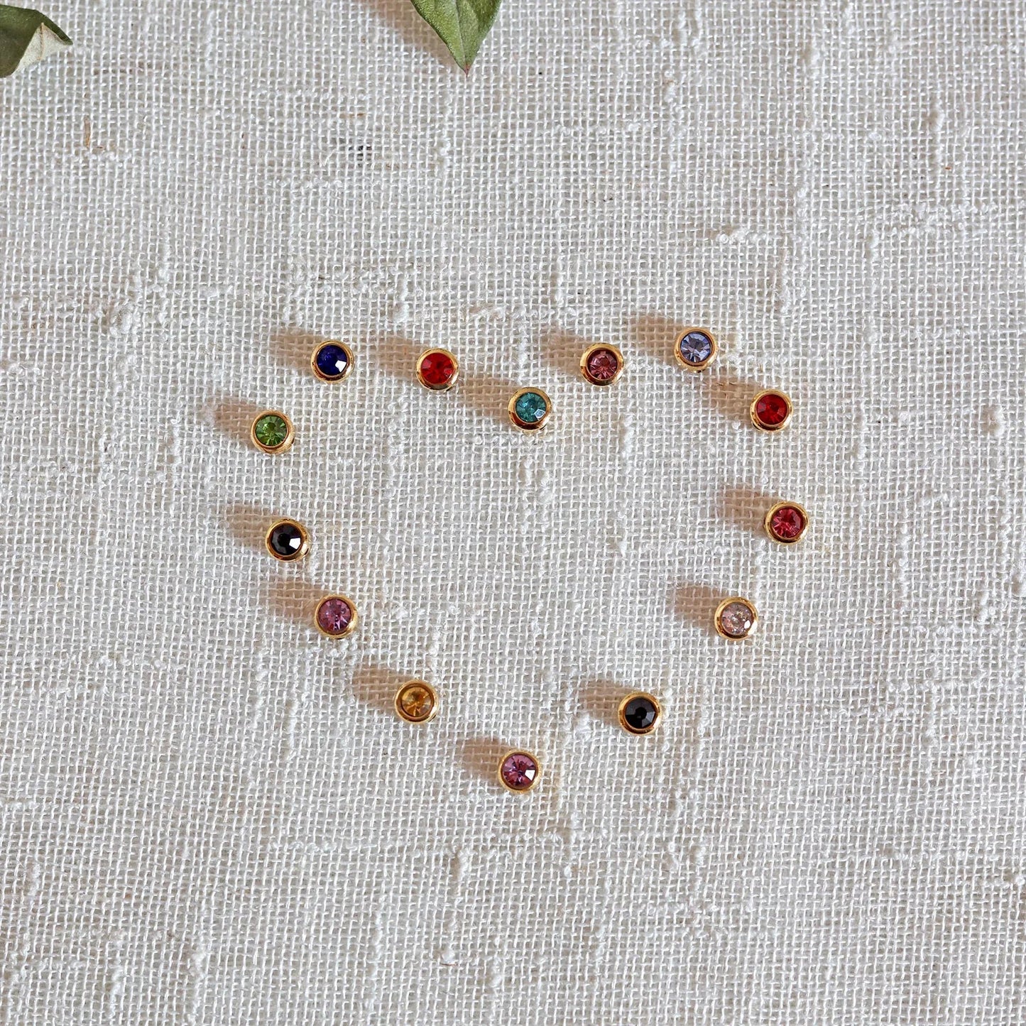 Pierres colorées en acier doré formant un coeur, posées sur un fond beige texturé.