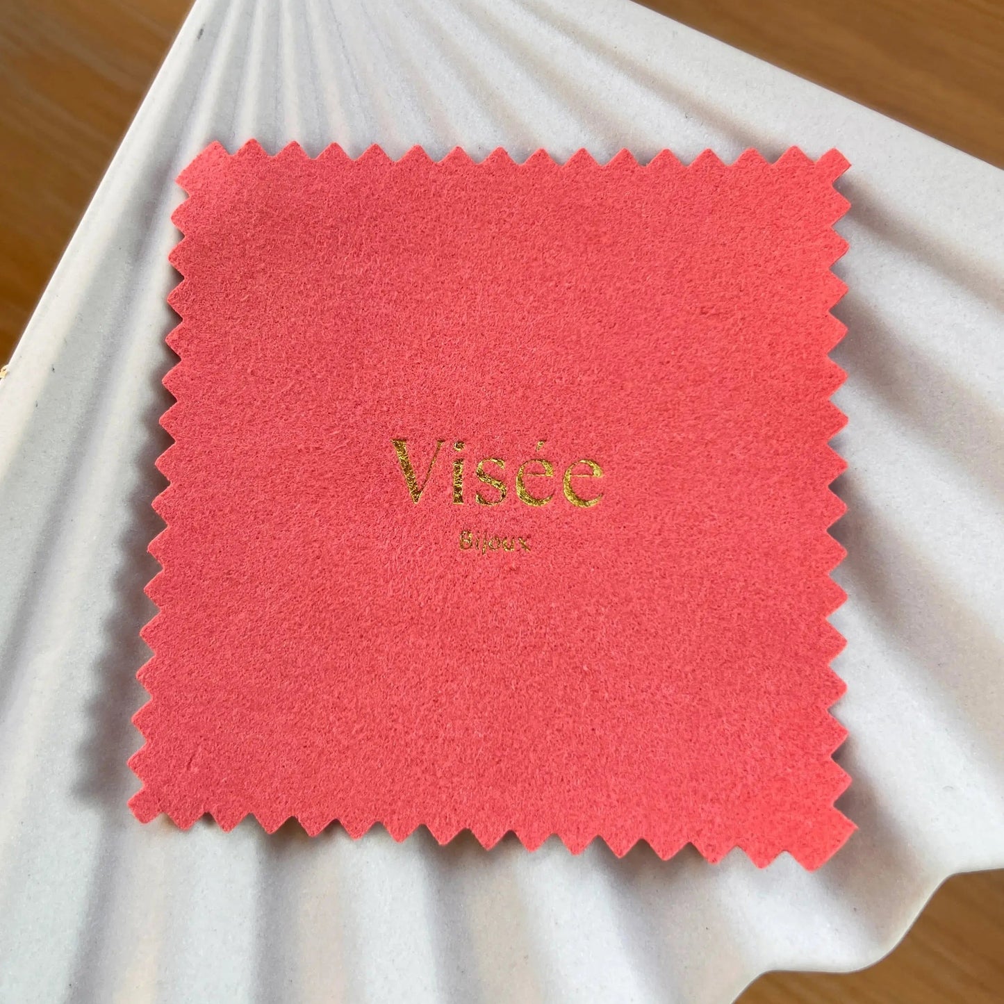 Chamoisine Visée en suédine corail, pour l'entretien délicat des bijoux, photographiée sur un fond beige.