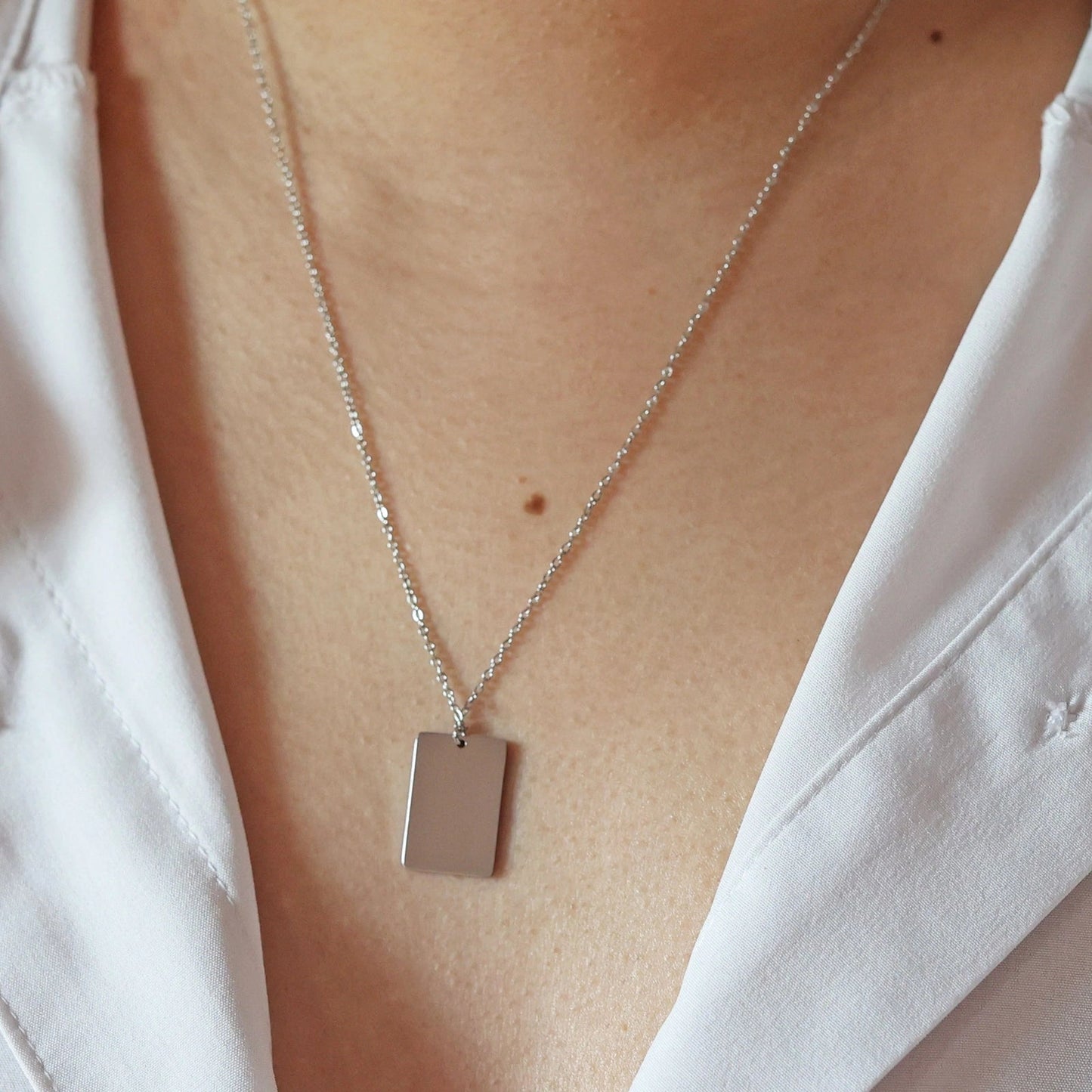 Collier "Je me souviens, en acier argenté, avec médaille rectangulaire à graver, porté autour du cou.