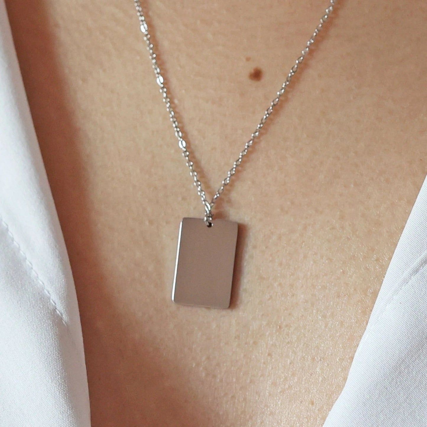 Collier "Je me souviens, en acier argenté, avec médaille rectangulaire à graver, porté autour du cou.