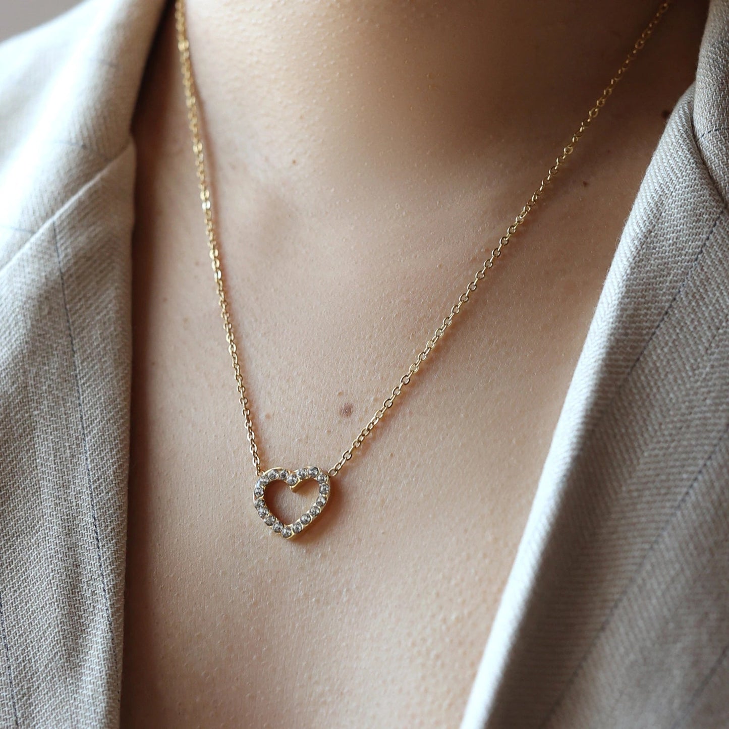 Collier Sentiment, avec pendentif cœur serti de brillants en acier inoxydable doré, porté autour du cou.