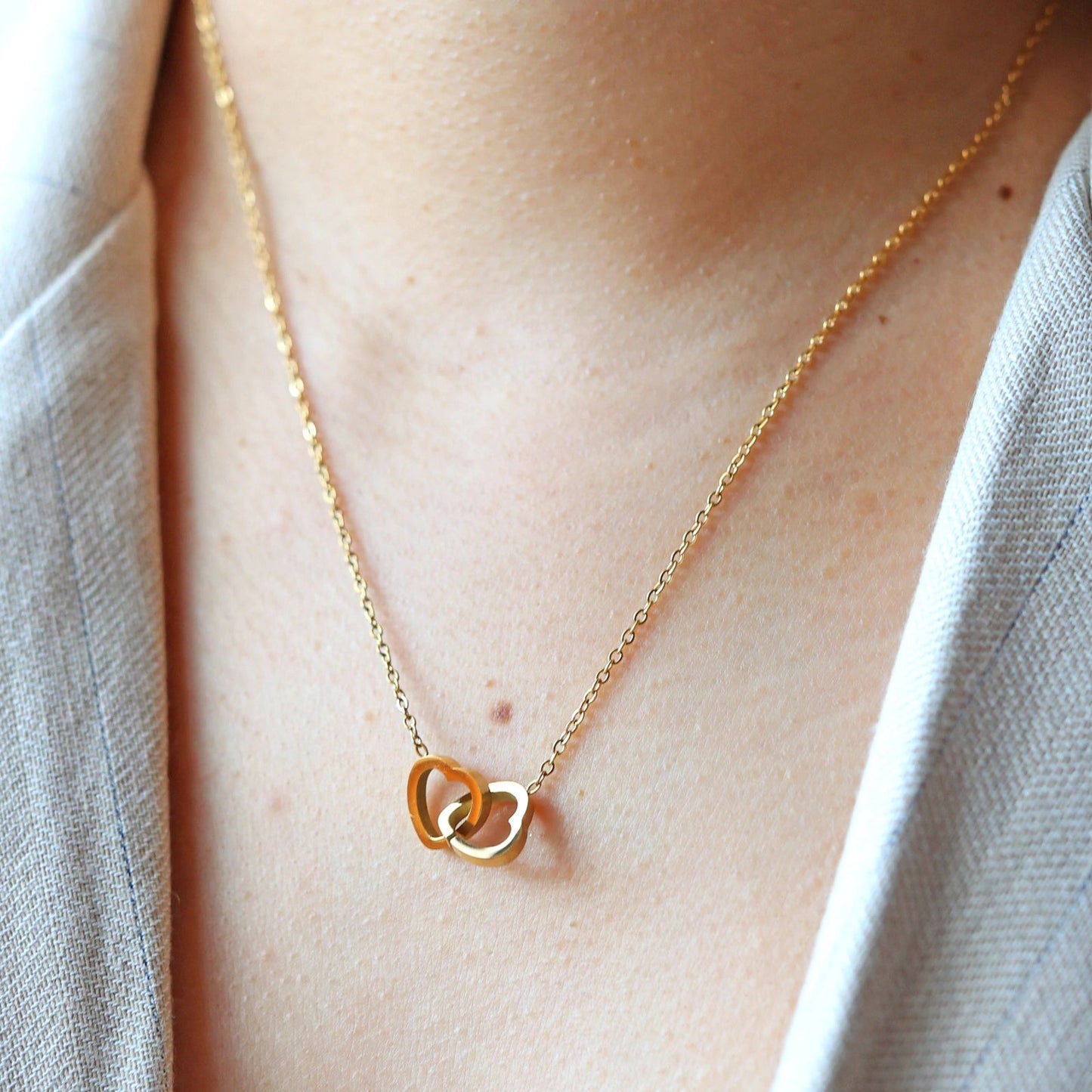 Collier Toi et moi en acier inoxydable doré, deux coeurs entrelacés, porté au cou.