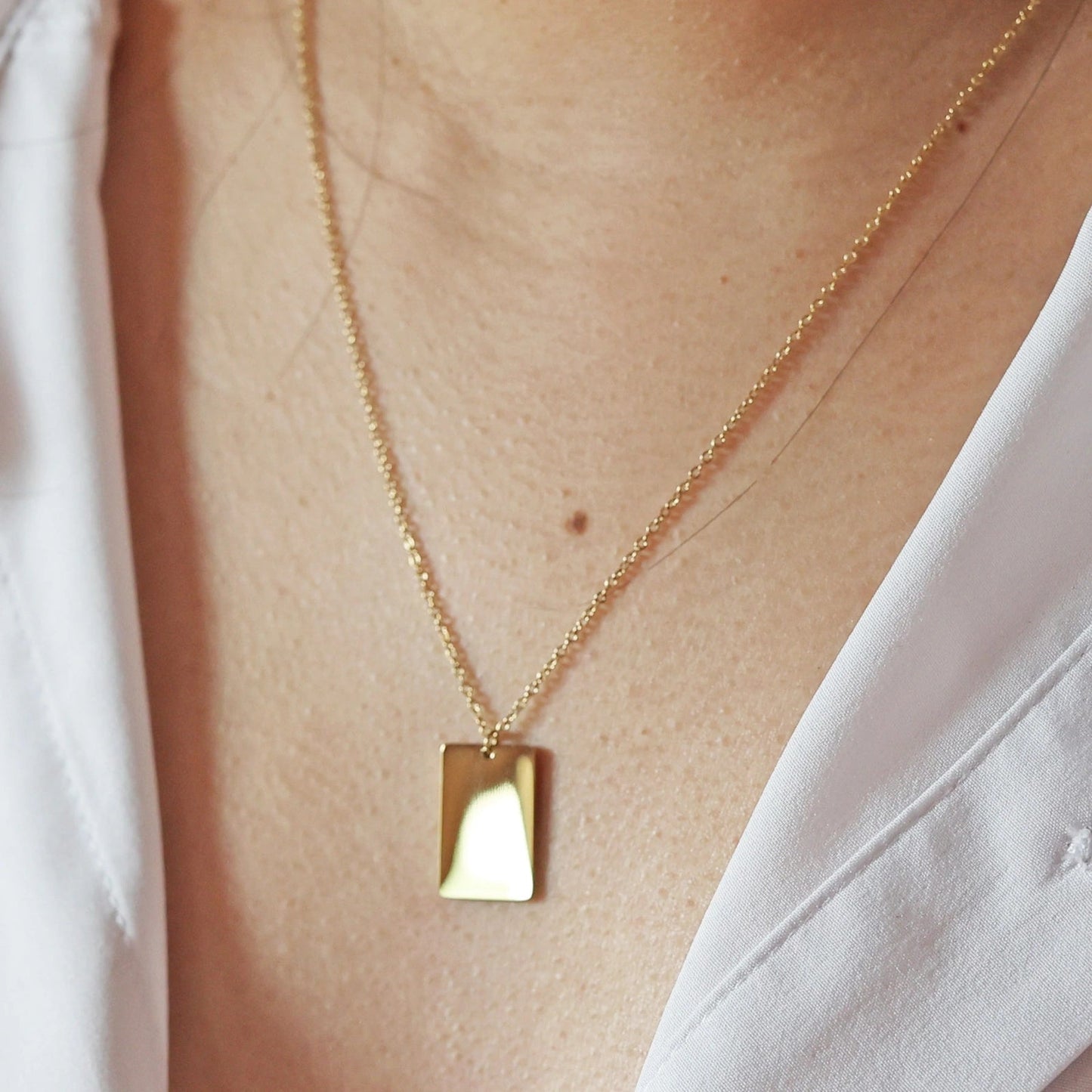 Collier "Je me souviens, en acier doré avec médaille rectangulaire à graver, porté autour du cou.
