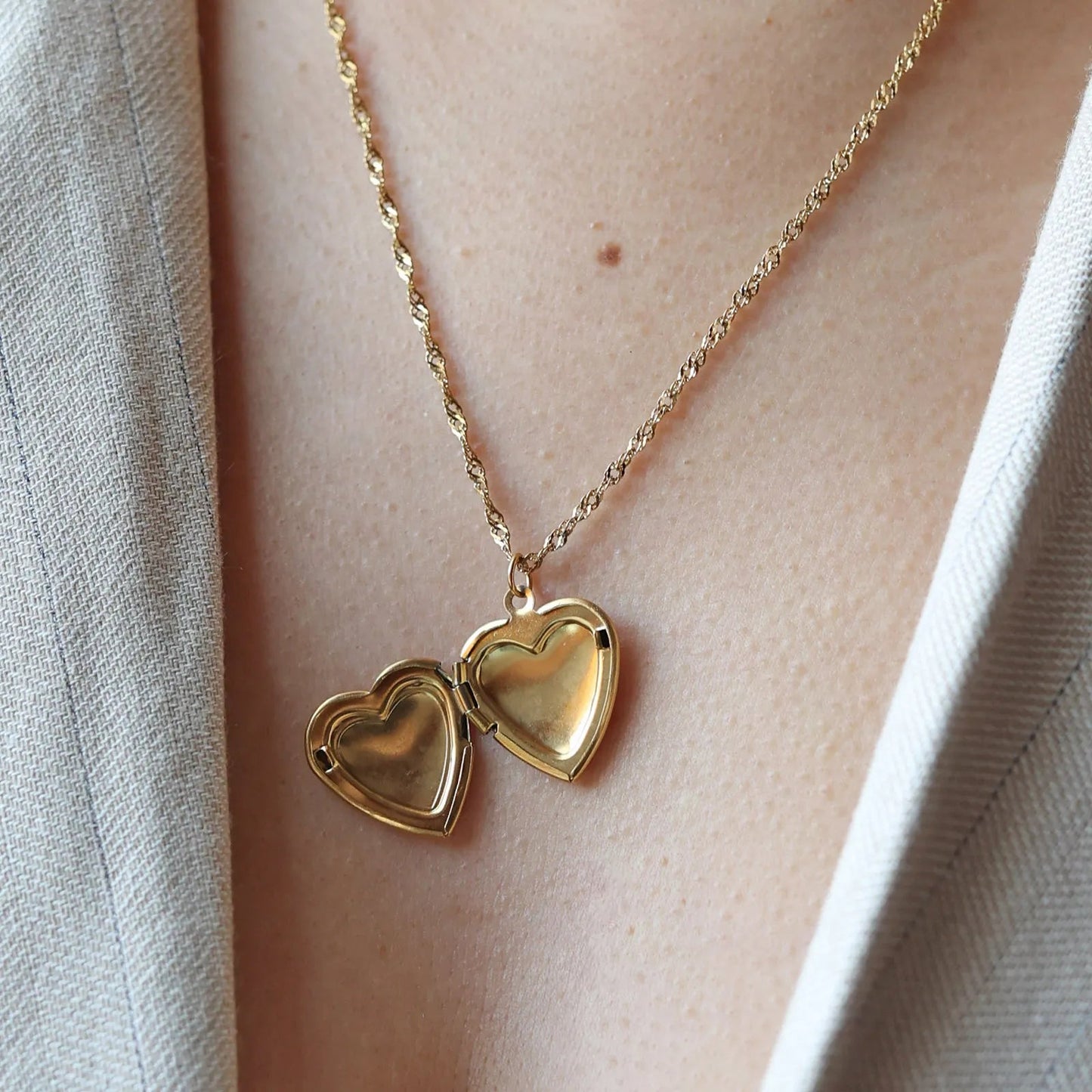 Collier "Entre nous", médaillon cœur ouvert en acier doré avec photo souvenir à personnaliser, porté autour du cou.