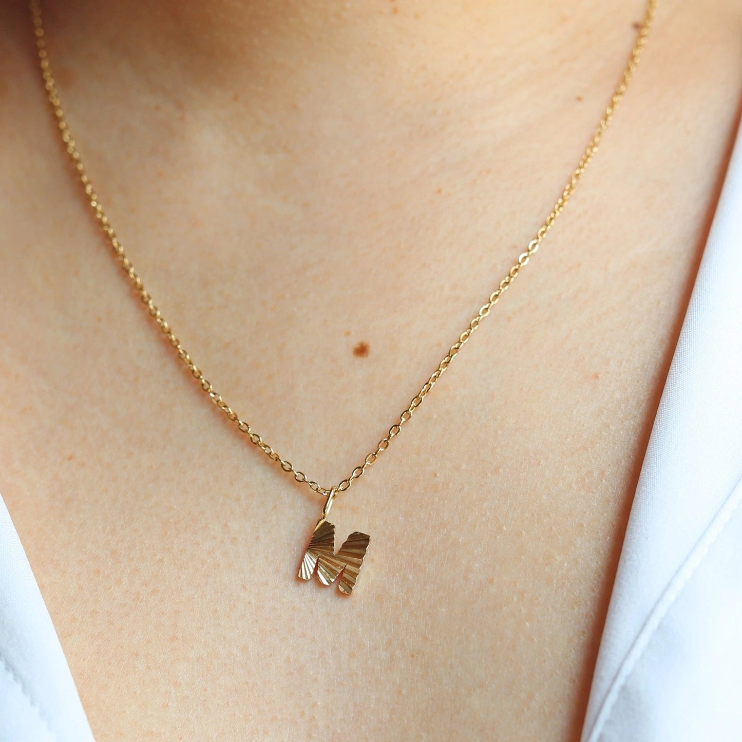 Collier "Je suis" avec pendentif lettre C striée, en acier doré, porté au cou.