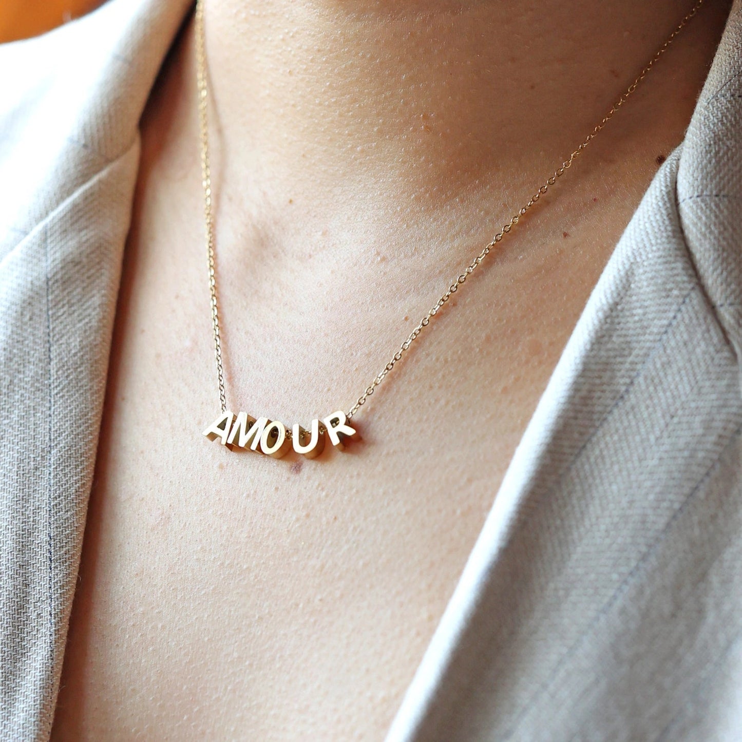 Collier L'instant avec lettres AMOUR dorées, en acier inoxydable, porté au cou.