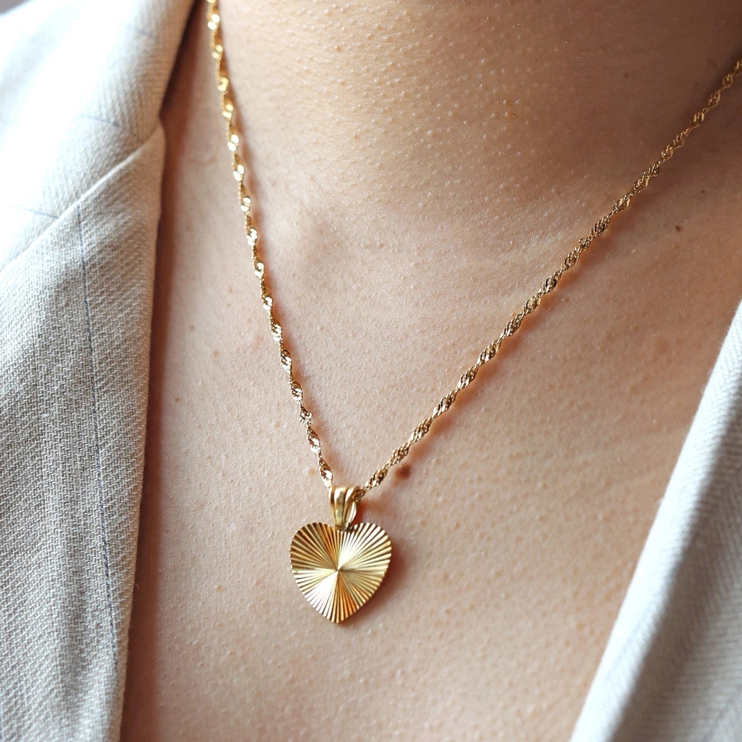 Collier A coeur ouvert porté au cou - pendentif cœur strié en acier doré personnalisé, chaîne torsadée.