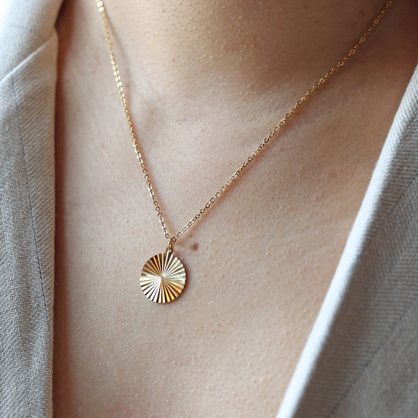 Collier "Energie" avec pendentif rond strié personnalisé en acier doré, porté autour du cou.