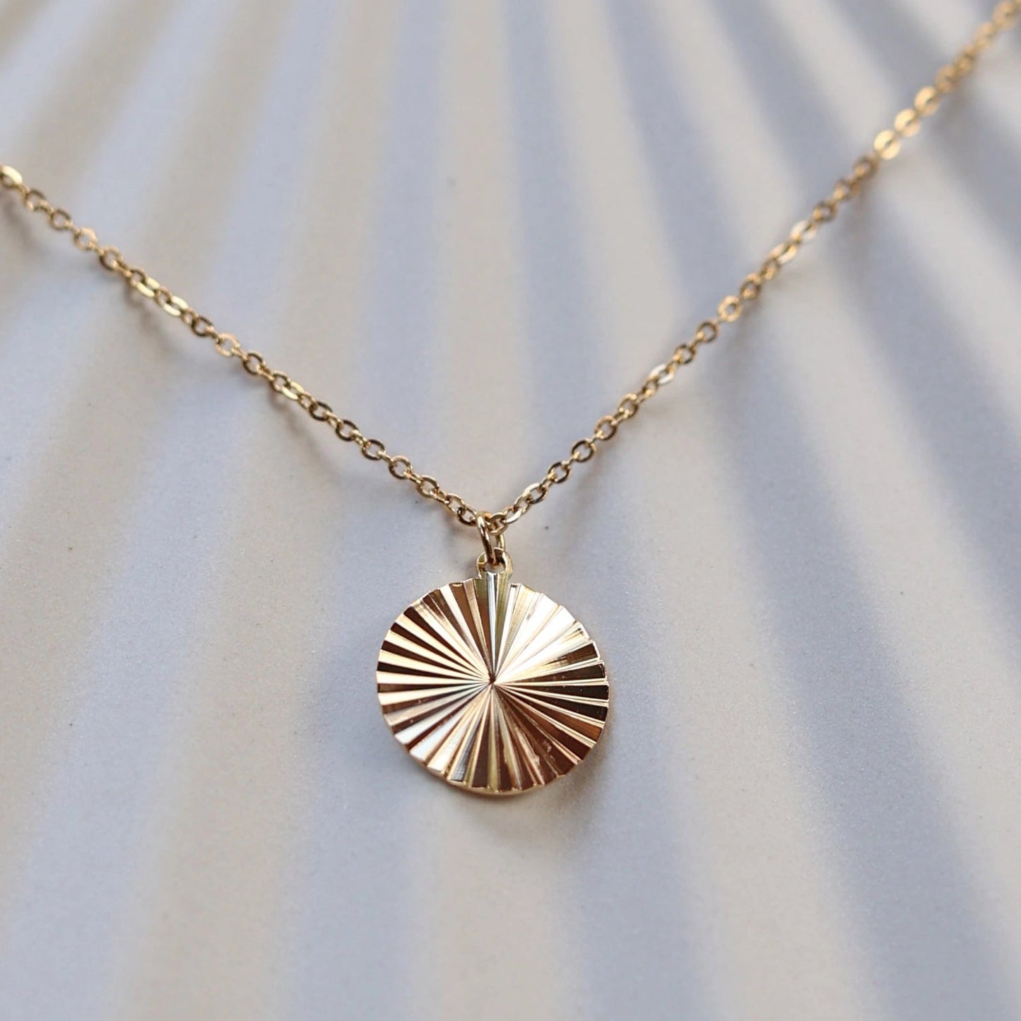 Zoom sur le collier "Energie" avec pendentif rond strié personnalisé en acier doré.