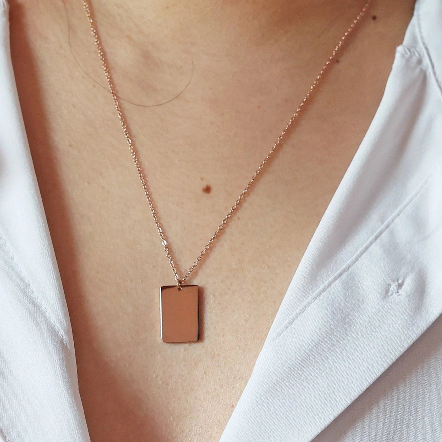 Collier "Je me souviens, en acier rosé, avec médaille rectangulaire à graver, porté autour du cou.