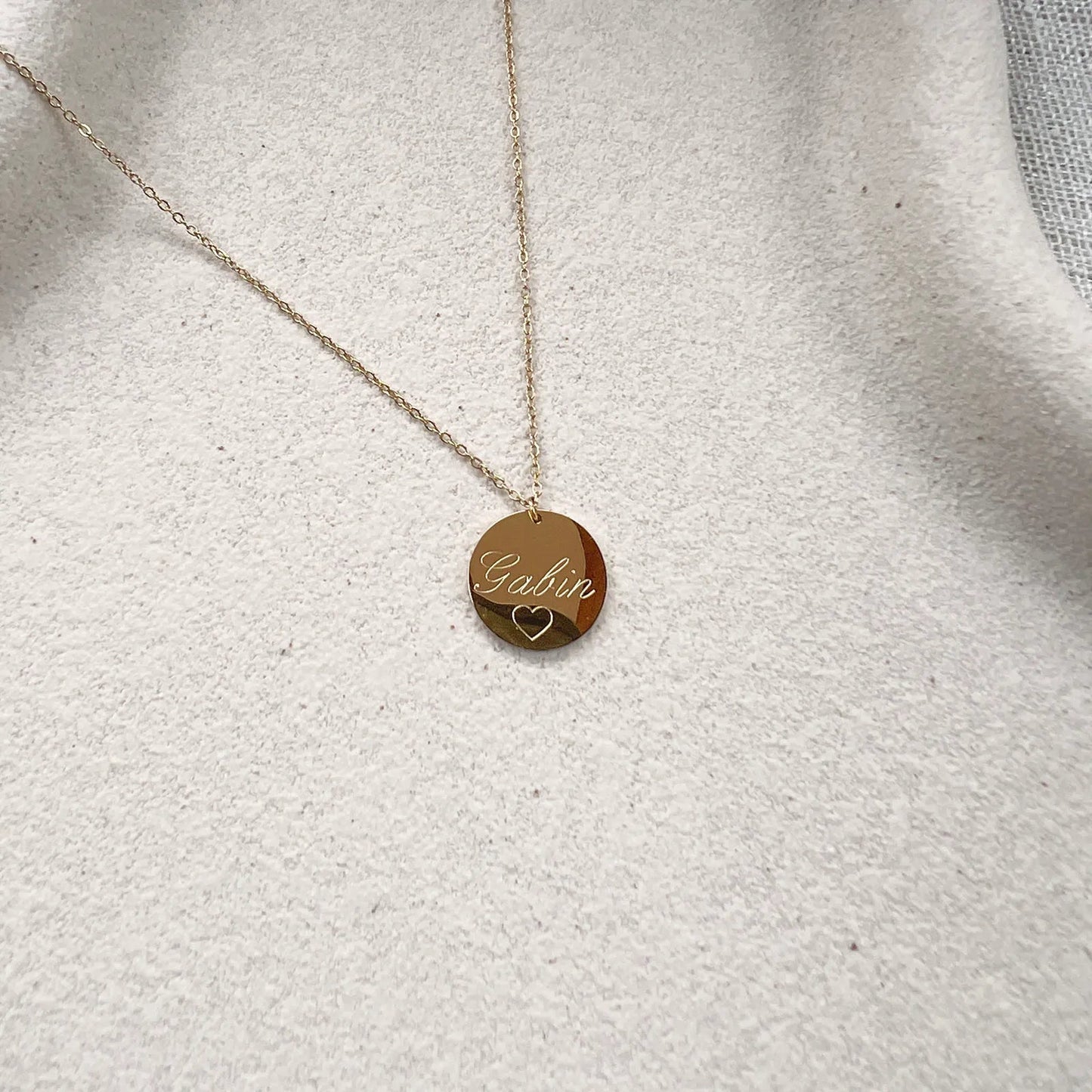 Zoom sur le collier "Reflet" avec médaille ronde personnalisé "Gabin" en acier inoxydable rosé.