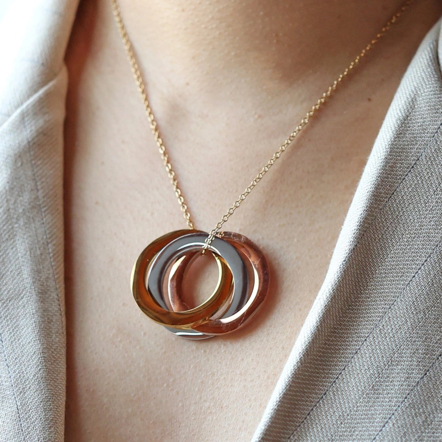 Collier "Je deviens" en acier doré, avec trois cercles entrelacés personnalisables, porté autour du cou.