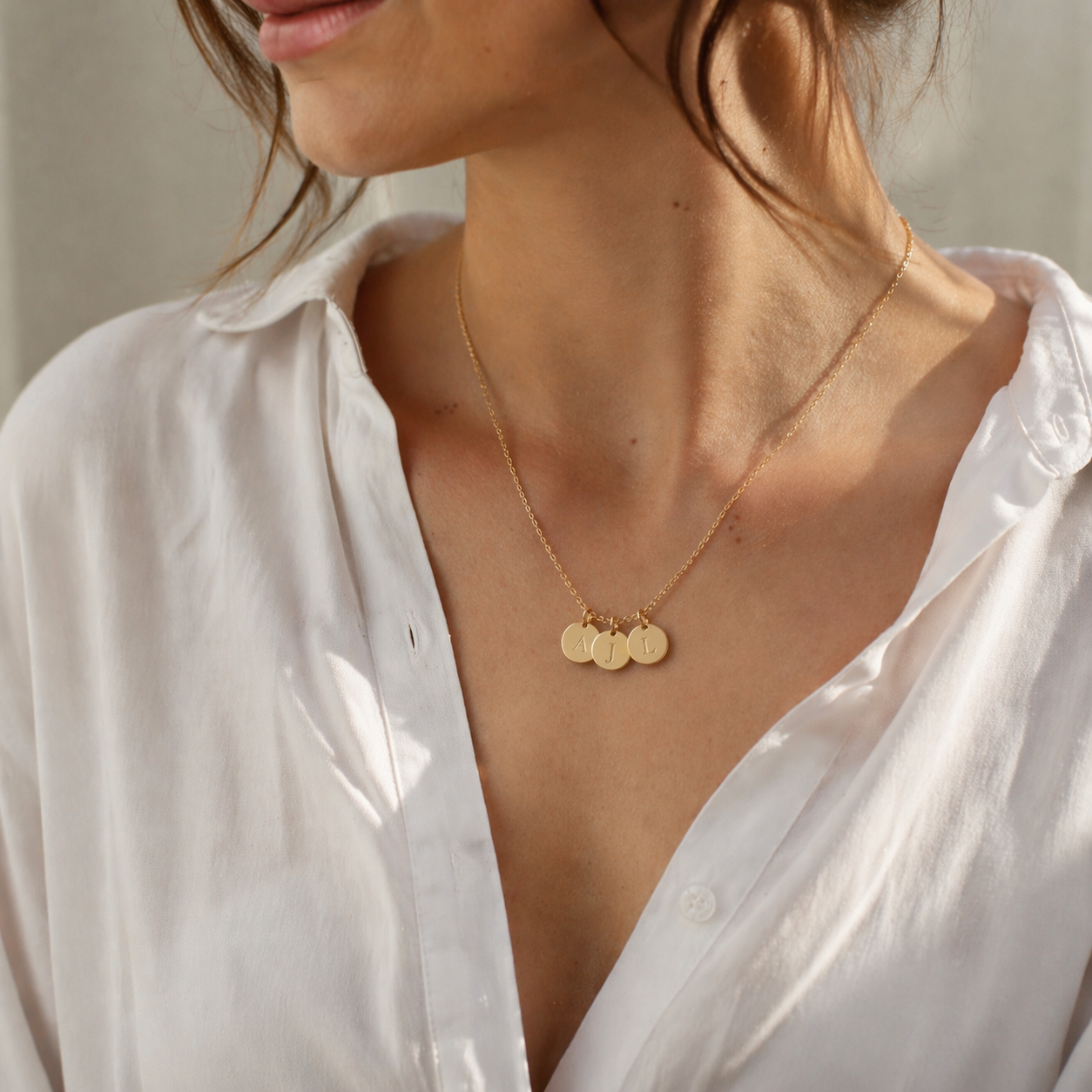 Collier gravé avec les initiales A J L, portée sur mannequin avec chemise blanche