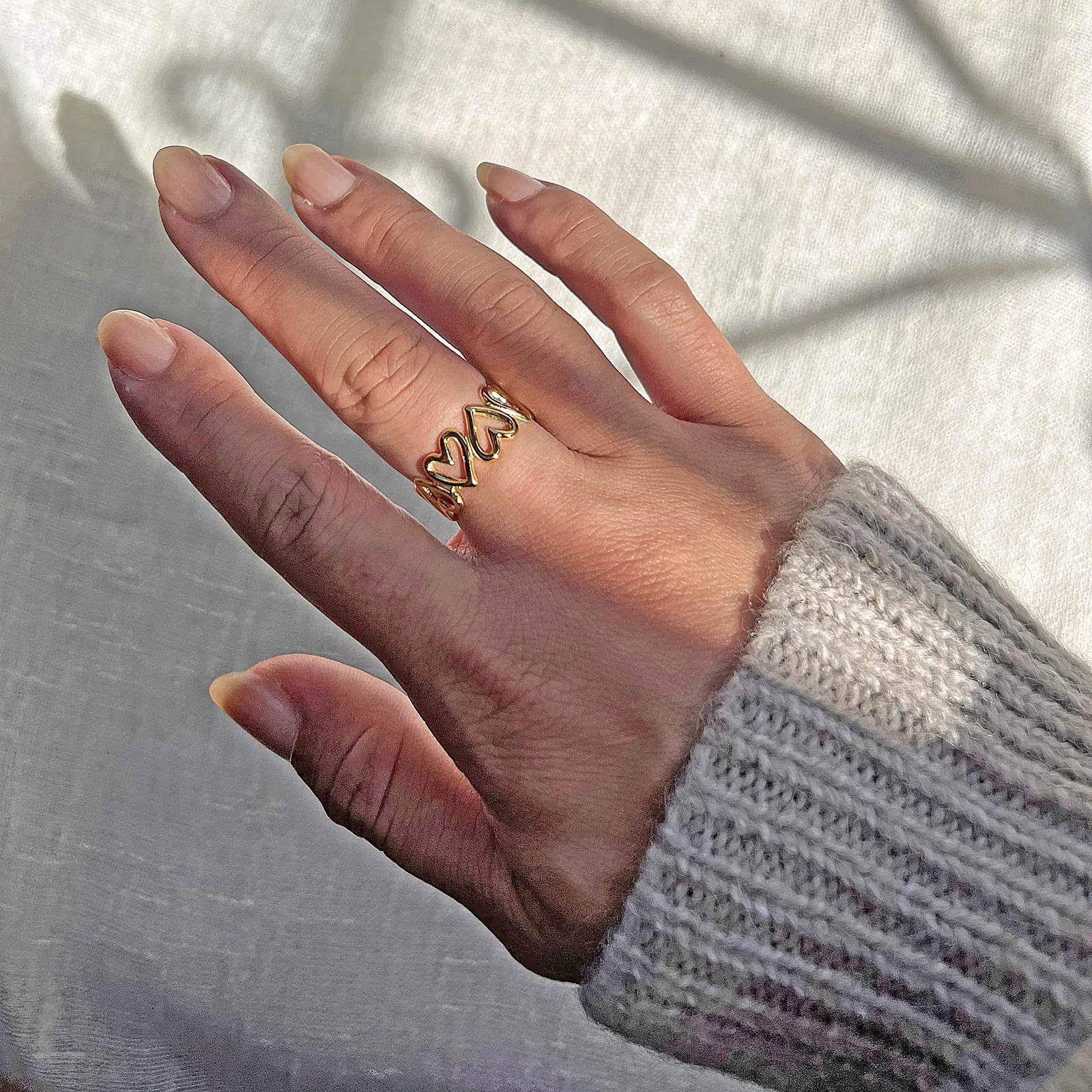 Bague ajustable Mon message, en acier inoxydable doré, orné de coeurs, portée à la main. 