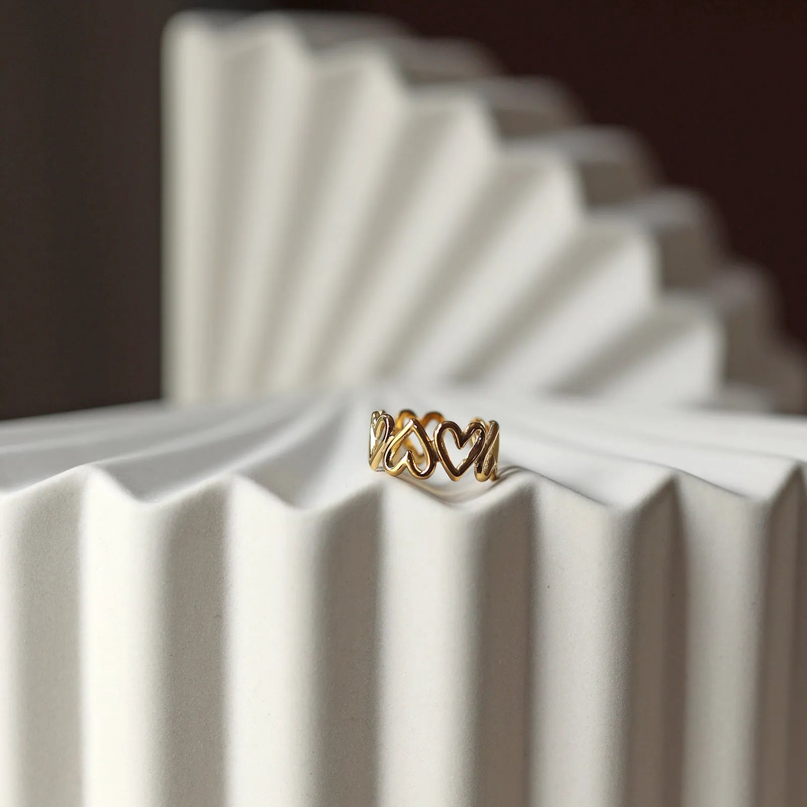 Bague ajustable Mon message, en acier inoxydable doré, orné de coeurs, posée à plat sur un support texturé beige clair.