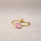 Bague pierre de couleur rose de 8 mm Visée Facette gros plan, posées à plat sur un fond beige texturé.