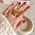 Bague "Je me dévoile" réglable en acier inoxydable doré à motif sculpté, portée à la main.