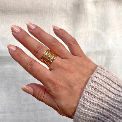 Bague J'ai changé multi-rang ajustable  en acier inoxydable doré, portée à la main, vue portée sur fond beige avec pull en maille.