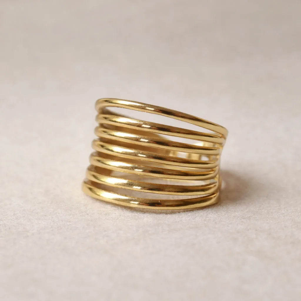 Bague J'ai changé multi-rang ajustable en acier inoxydable doré posée à plat sur un tissu beige doux, vue zoom