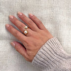 Bague Rencontre ouverte en acier inoxydable doré, ornée de deux perles blanches - effet portée à la main.