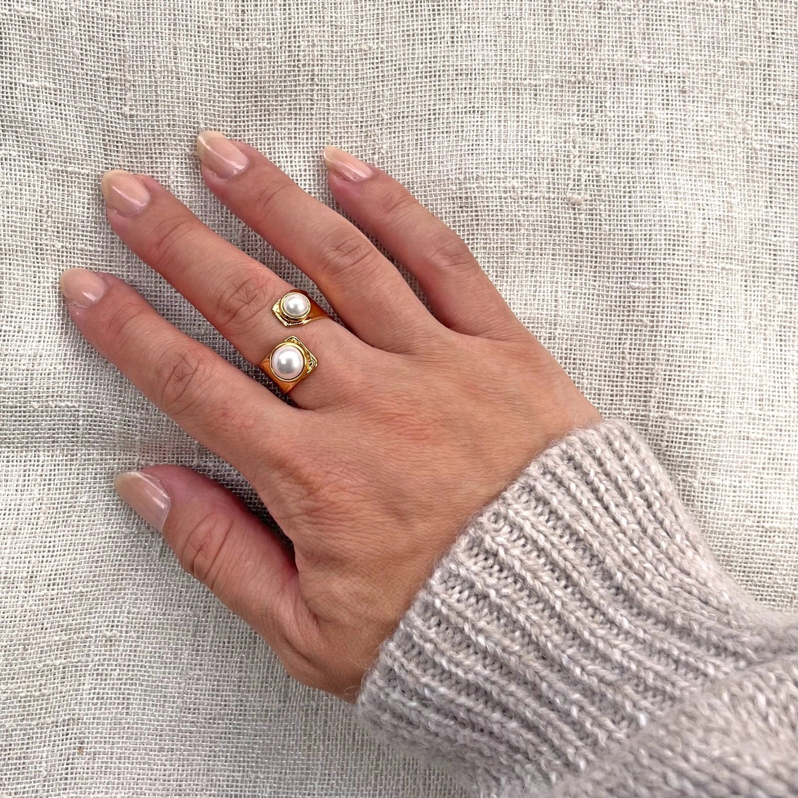 Bague Rencontre ouverte en acier inoxydable doré, ornée de deux perles blanches - effet portée à la main.