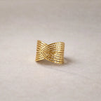 Bague Entrelacs ajustable, au design géométrique en acier inoxydable doré, posée sur un fond beige texturés