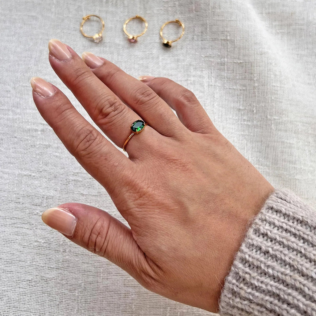 Bague "Mes Facettes" ajustable, ornée d'une pierre verte, portée autour du doigt.