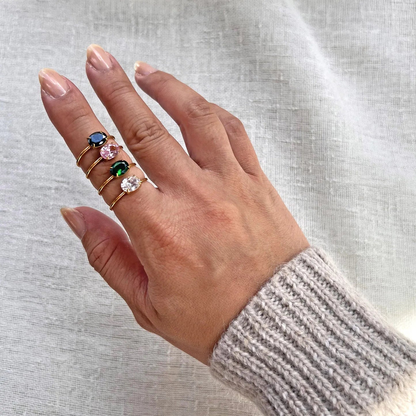 Bague "Mes Facettes" ajustable, en acier doré, ornée d'une pierre de couleur, portées sur une main féminine. 