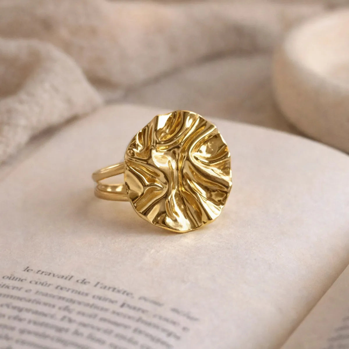 Bague Froissé Visée vue de biais  lumière naturelle, posée sur un livre ouvert. 