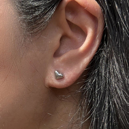 Boucles d'oreilles "Tendre discrétion" de Visée, en forme de cœur en acier argenté, portées à l'oreille.