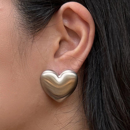 Boucles d'oreilles "S'aimer", en maxi cœurs argentés mat, en acier Inoxydable, portées à l'oreille.
