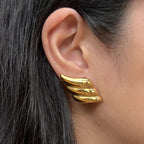 Boucles d'oreilles ailes dorées - Envolée Visée Bijoux, portée sur oreille d'une mannequin