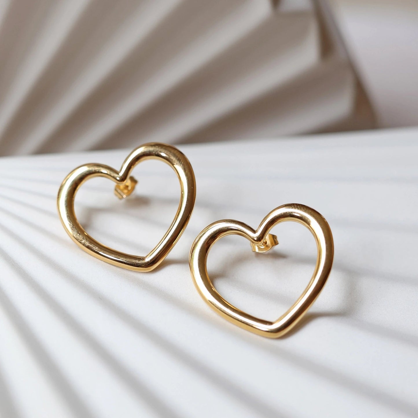 Boucles d'oreilles Douce force en acier doré, grands coeurs en gros plan.