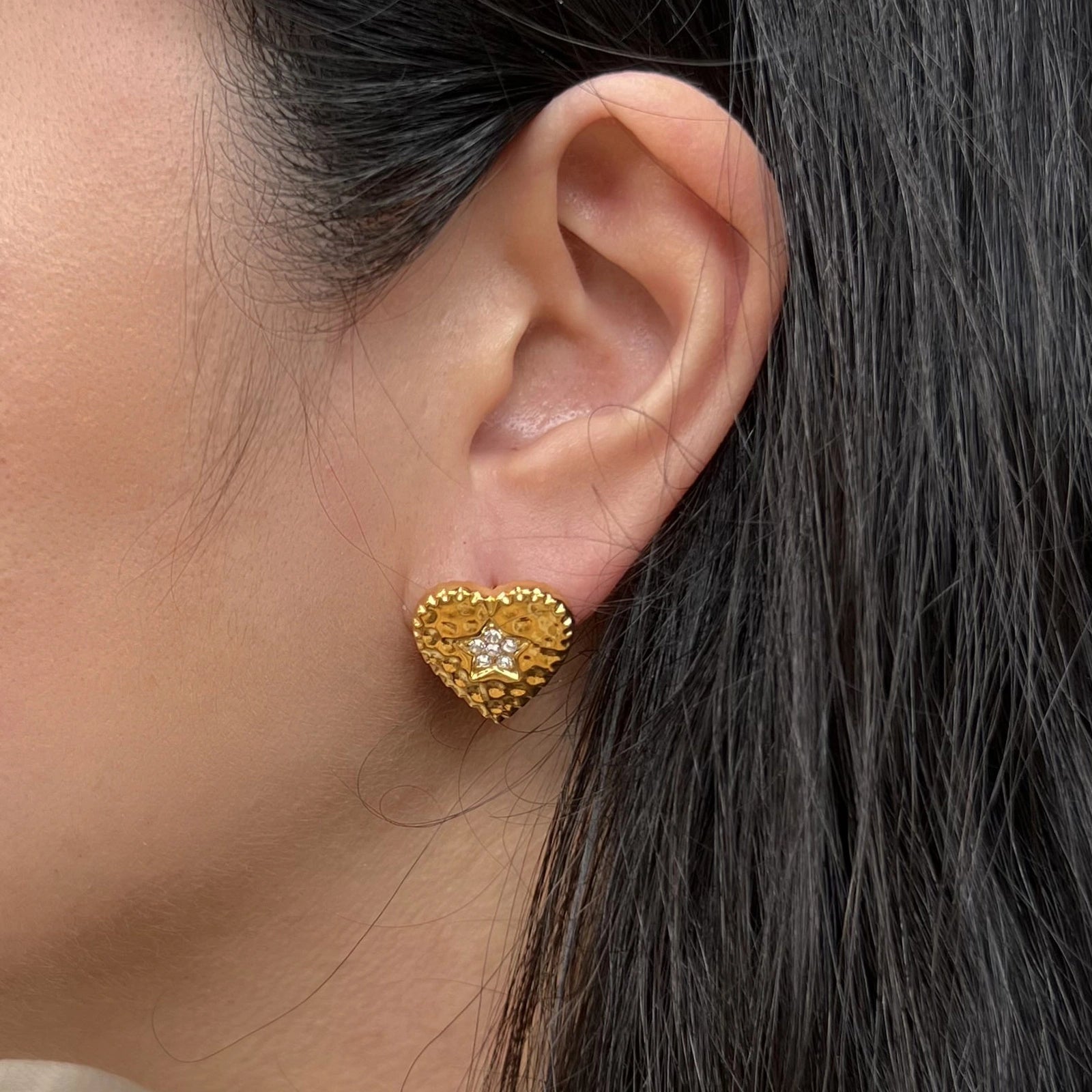 Boucles d'oreilles Promesse, en forme de cœur ornées d'une étoile, en acier inoxydable doré, portées à l'oreille.