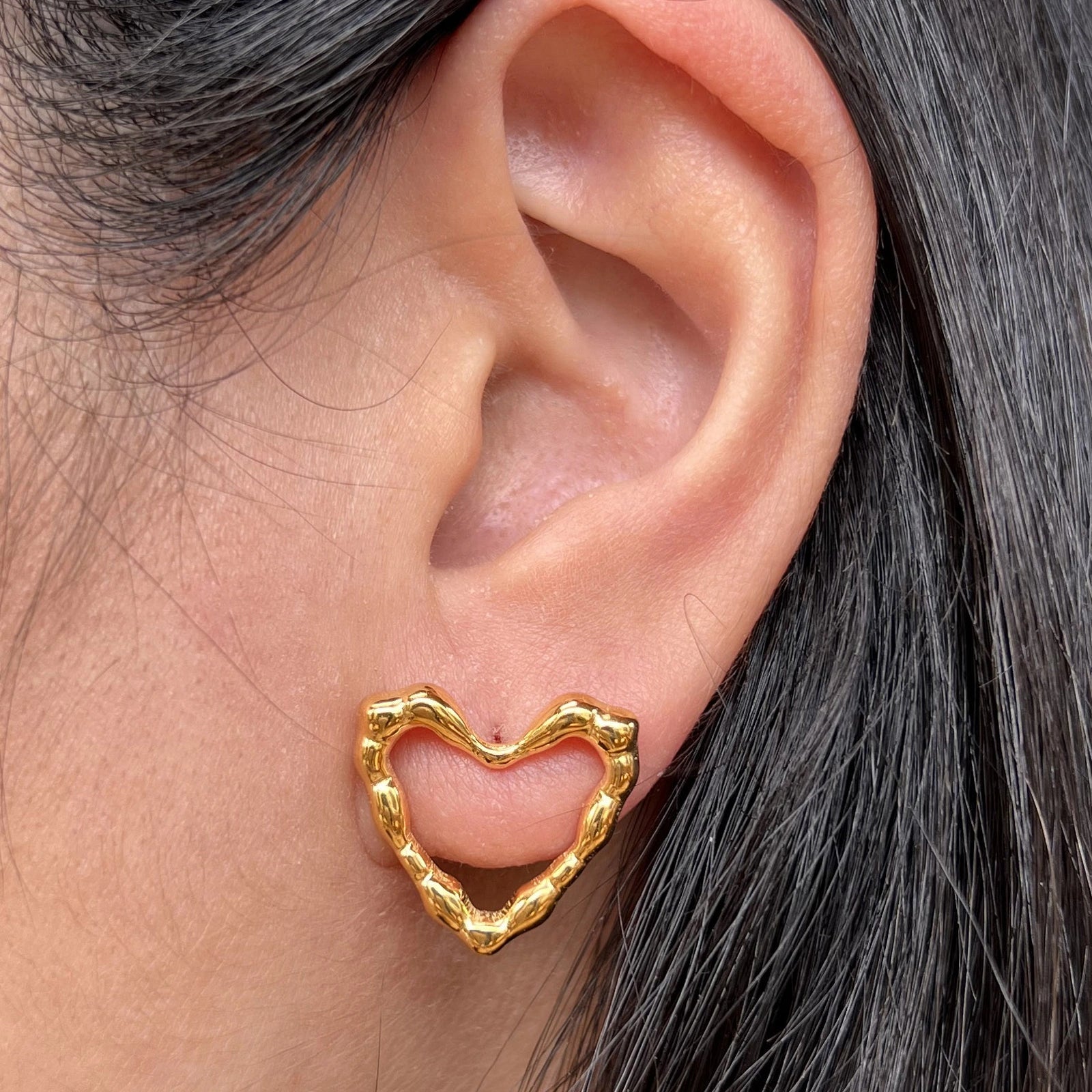 Boucles d'oreilles charismatique, en forme de cœur martelé, en acier inoxydable doré, porté à l'oreille.
