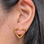 Boucles d'oreilles Insolente Douceur, en forme de cœur martelé, en acier inoxydable doré, porté à l'oreille.
