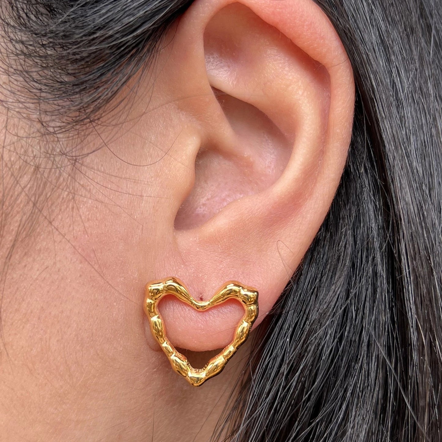 Boucles d'oreilles Insolente Douceur, en forme de cœur martelé, en acier inoxydable doré, porté à l'oreille.
